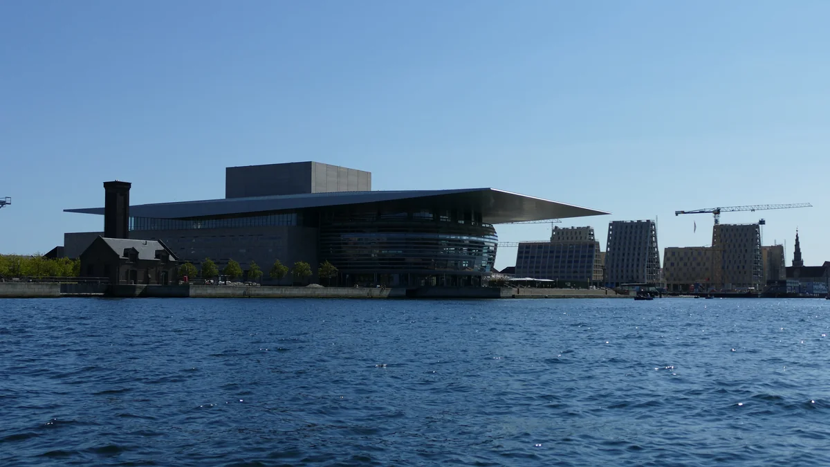 Ópera de Copenhague vista do outro lado da água sob céu azul