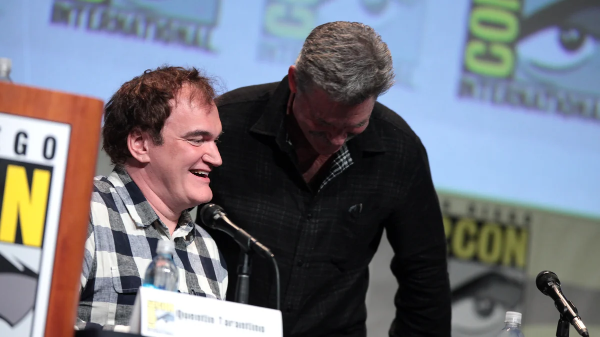 Quentin Tarantino laughs at a panel table as Kurt Russell leans beside him