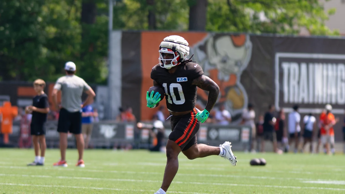 Quinshon Judkins, wearing a brown number 10 uniform and green gloves, runs on a practice field