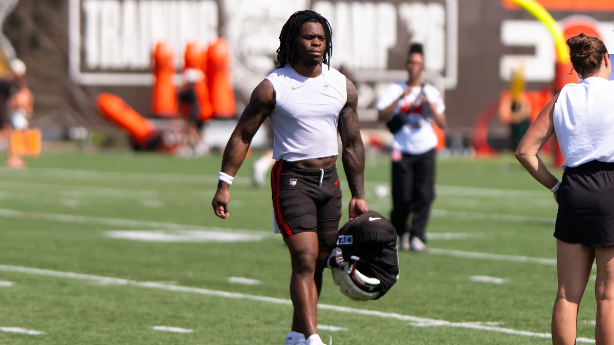 Quinshon Judkins walks across the field carrying a Browns helmet and protective gear