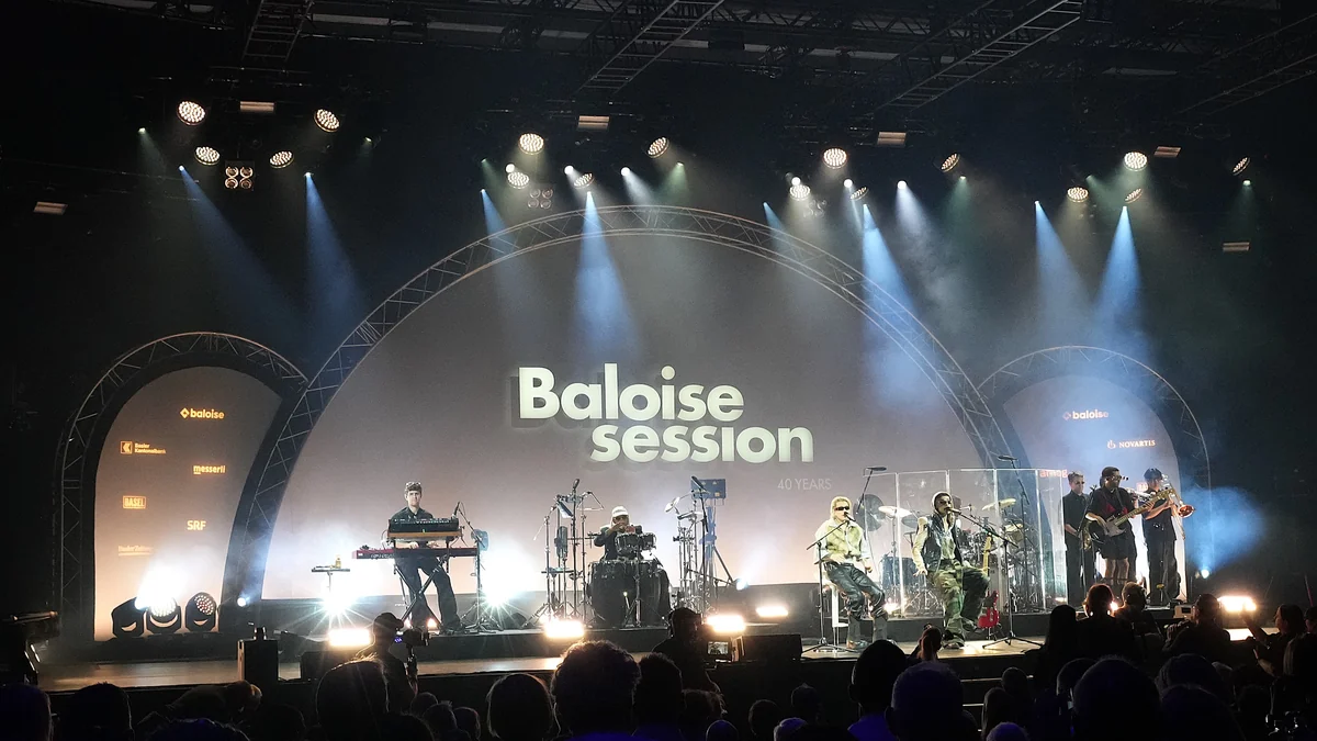 CA7RIEL y Paco Amoroso actúan con una banda ante el público en un escenario con luces azules