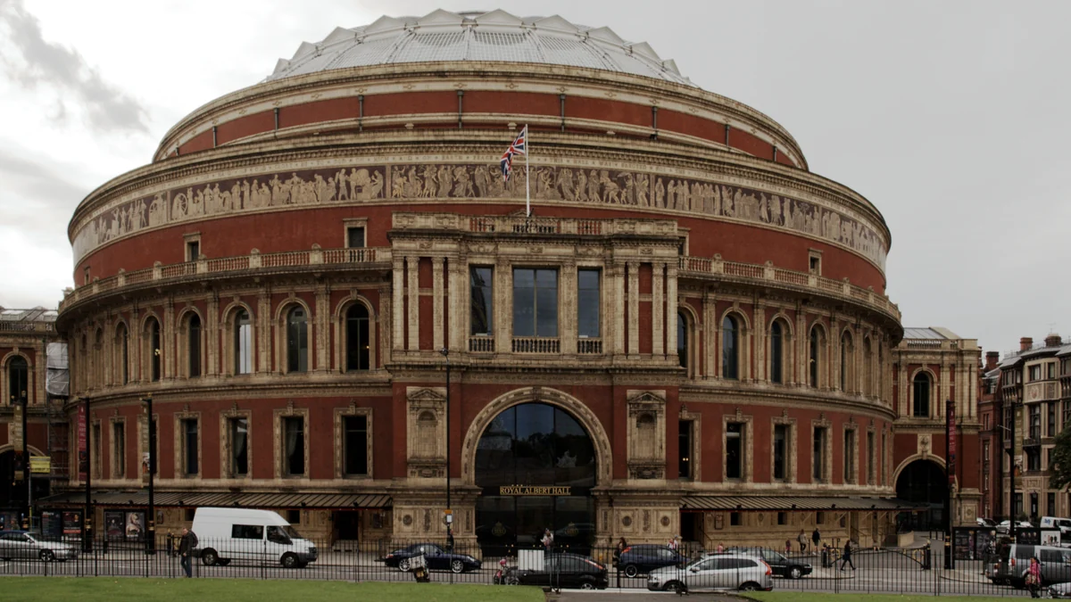 Façade circulaire du Royal Albert Hall sous un ciel nuageux, avec des voitures dans la rue