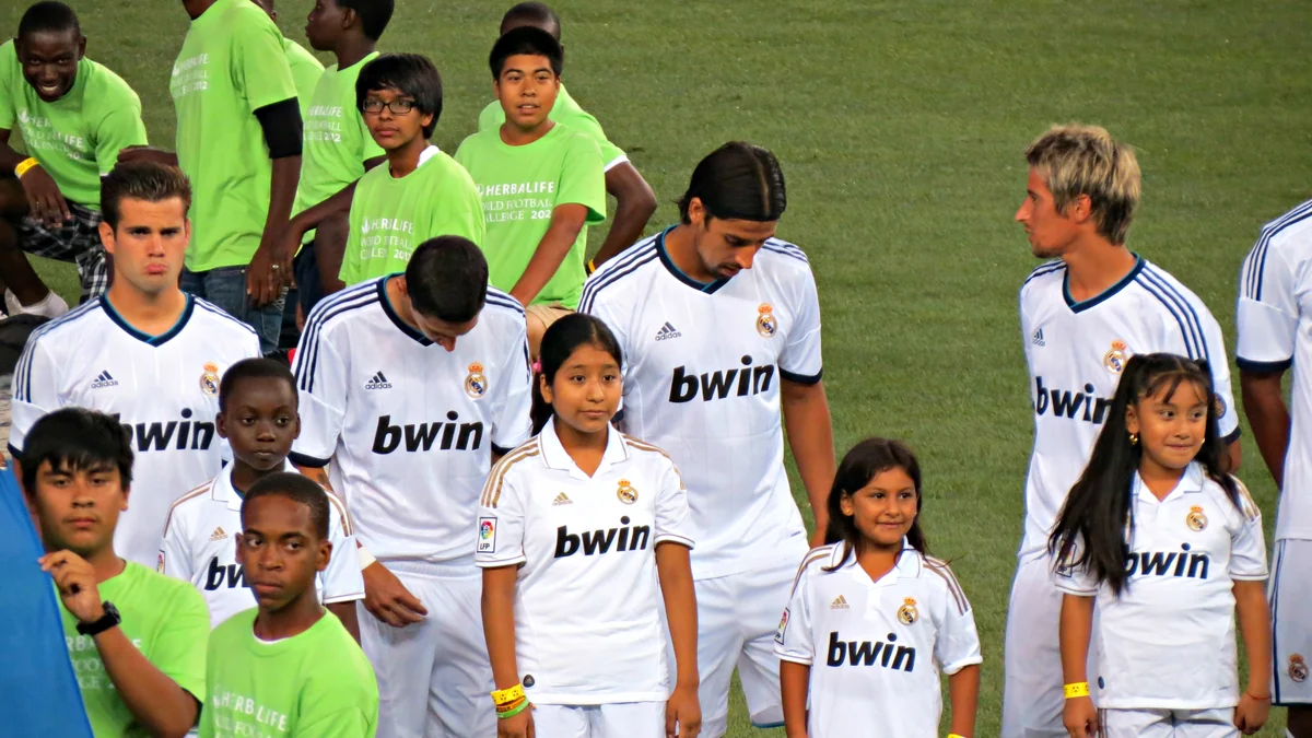 Joueurs du Real Madrid et enfants en maillot blanc alignés sur la pelouse