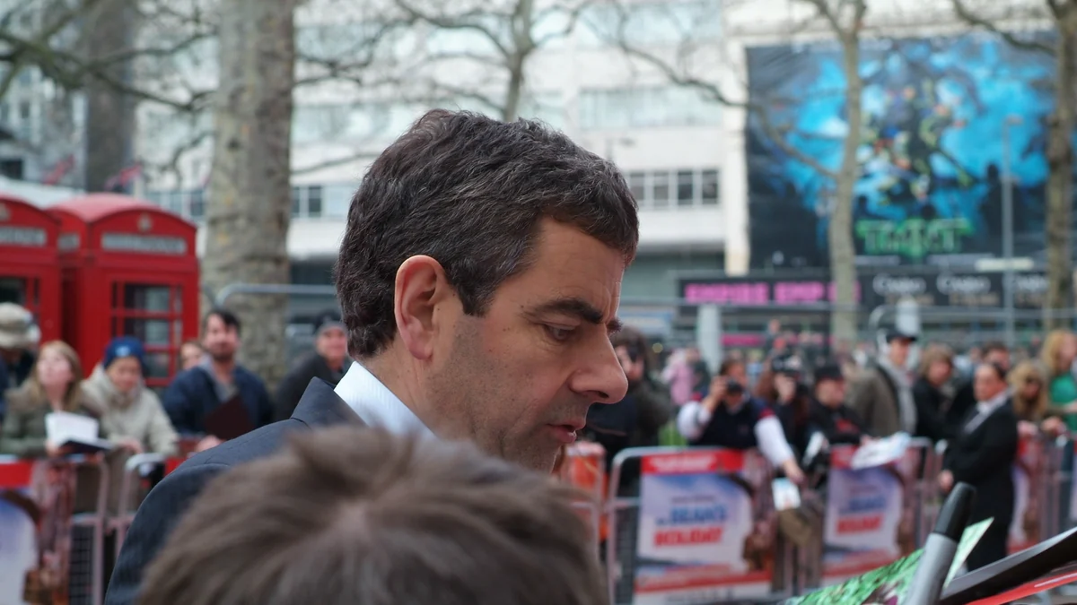 Rowan Atkinson de perfil ante fotógrafos y cabinas telefónicas rojas