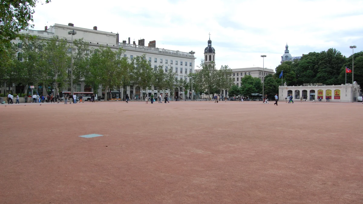 Open area of Place Bellecour with pedestrians, trees, and buildings in the background