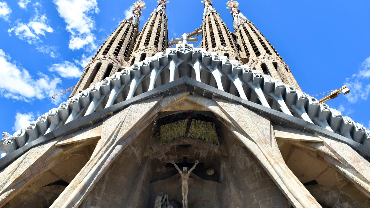 Fachada da Paixão da Sagrada Família vista de baixo, com torres e guindastes