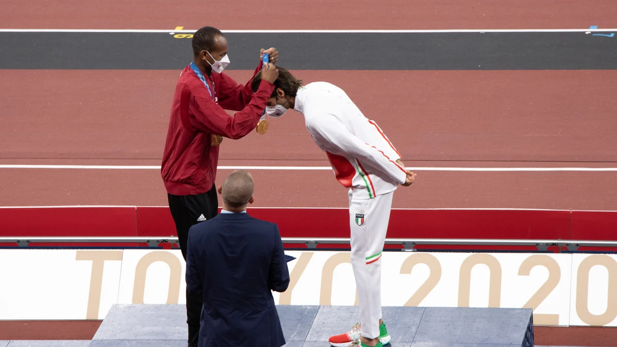 Mutaz Essa Barshim places a medal around Gianmarco Tamberi's neck on an athletics podium