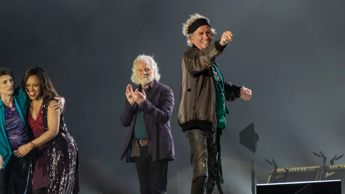 Keith Richards smiles and points toward the audience beside members of the Rolling Stones onstage