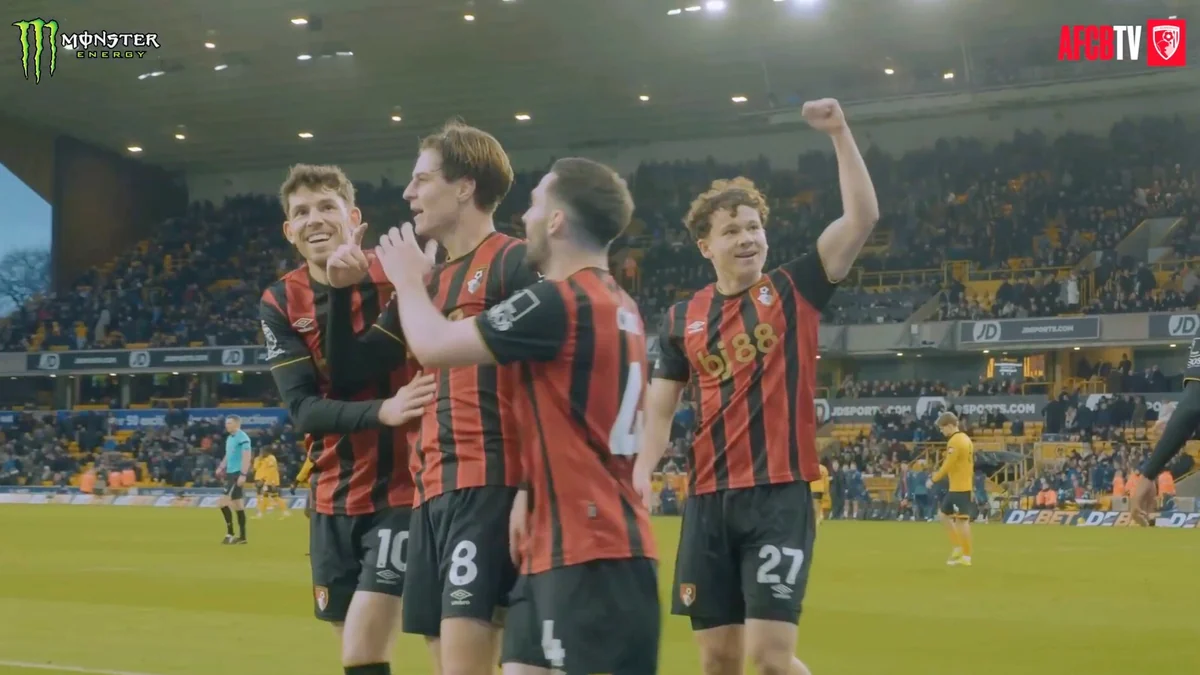 Quatre joueurs de Bournemouth en maillot rayé rouge et noir célèbrent sur la pelouse