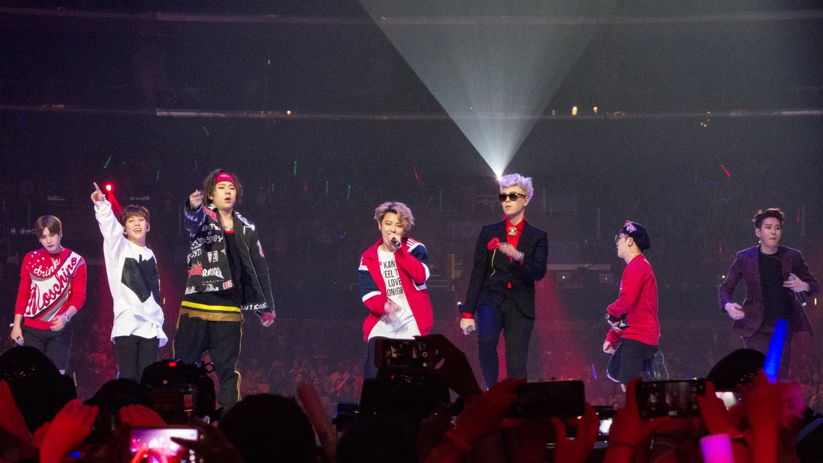 Sept membres de Block B se produisent sur scène devant des fans munis de téléphones et de bâtons lumineux