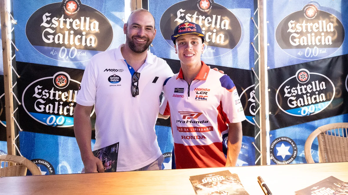 Diogo Moreira, en casquette et tenue Honda LCR, pose à côté d’un homme devant un panneau Estrella Galicia.