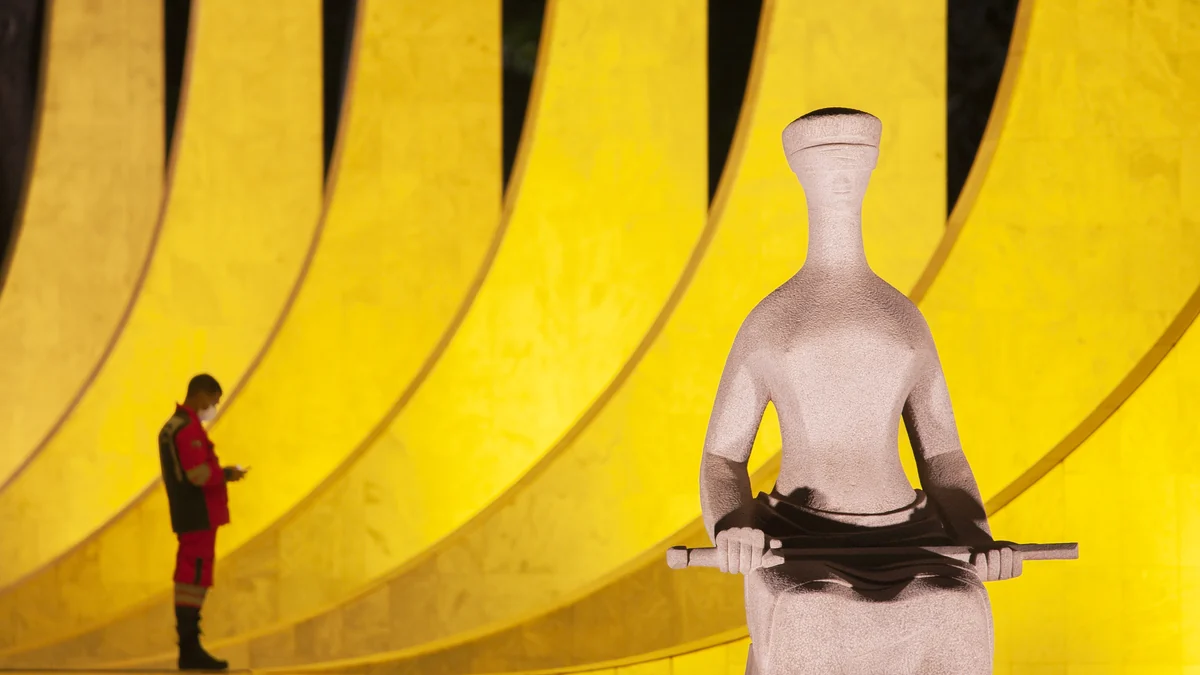 Sculpture de la Justice devant les colonnes courbes du Supremo Tribunal Federal éclairées en jaune
