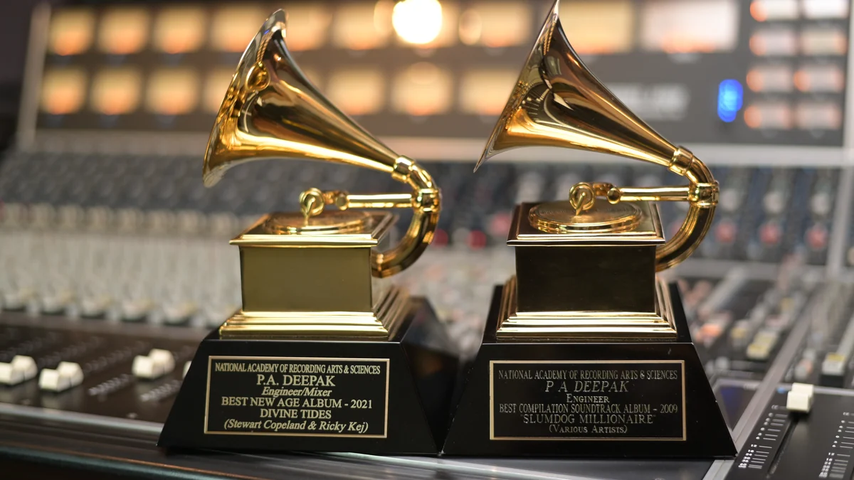 Dos trofeos dorados con forma de gramófono sobre una mesa de sonido