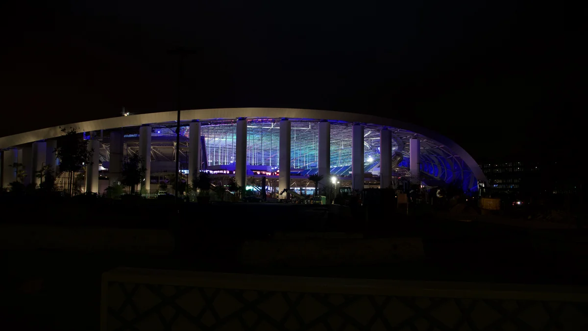 SoFi Stadium iluminado de azul por la noche, visto desde el exterior