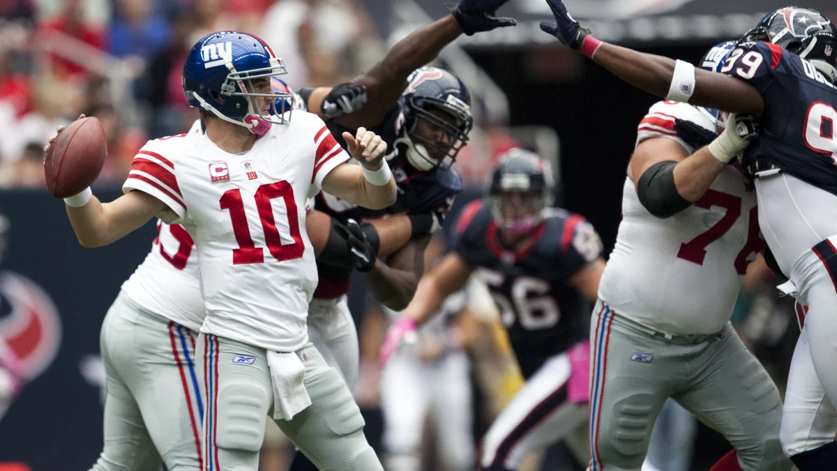 Eli Manning prépare une passe sous la pression de joueurs des Texans