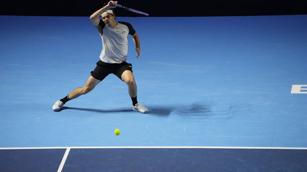 Taylor Fritz se déplace pour renvoyer une balle sur un court bleu