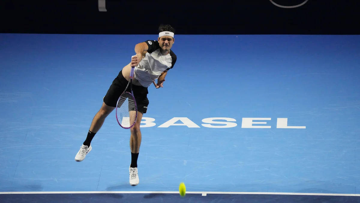 Taylor Fritz saute au service sur un court bleu où apparaît le mot Basel