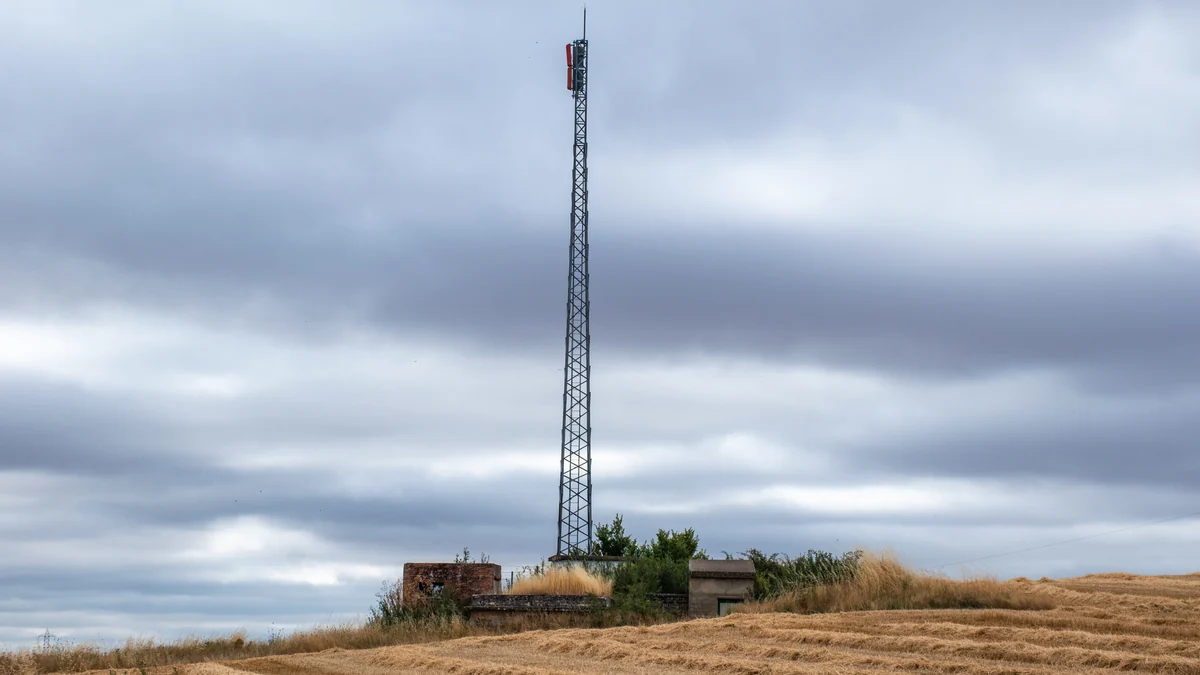 Torre metálica de repetidor de TDT em um campo sob céu nublado