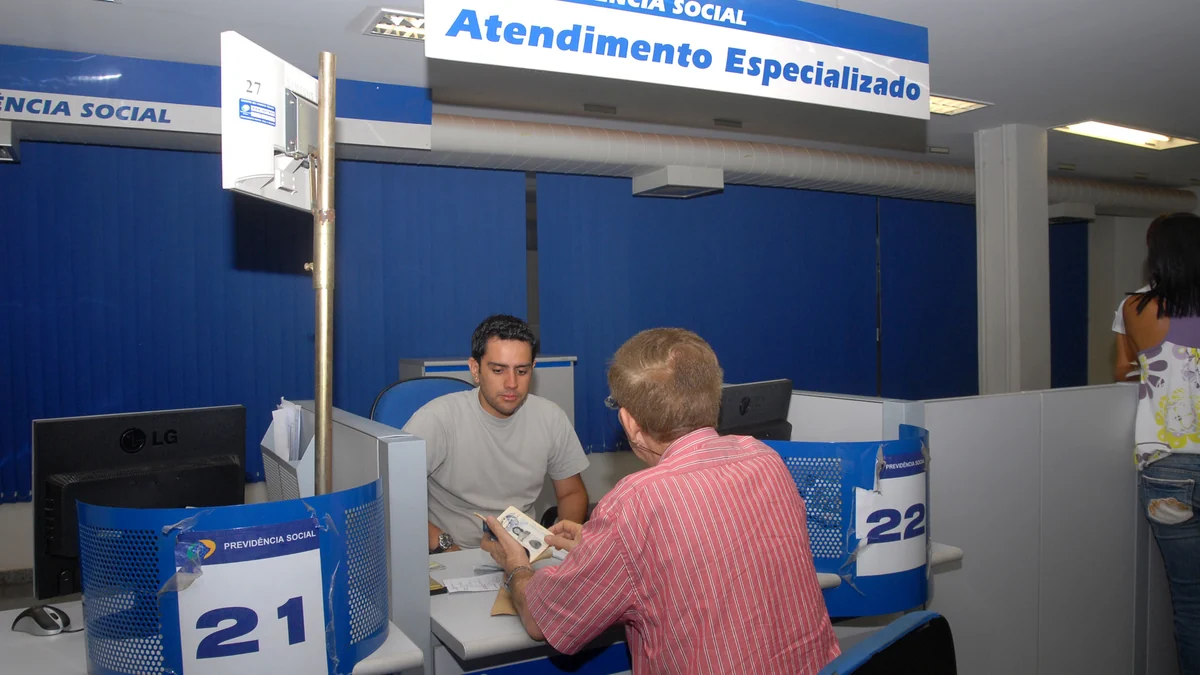 Insured person seated across from a clerk at a Brazilian Social Security service desk