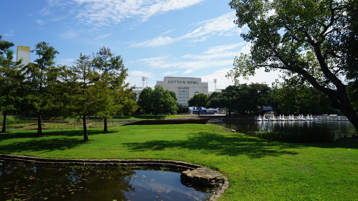 Cotton Bowl aperçu au fond d’un parc avec pelouses, arbres et étang