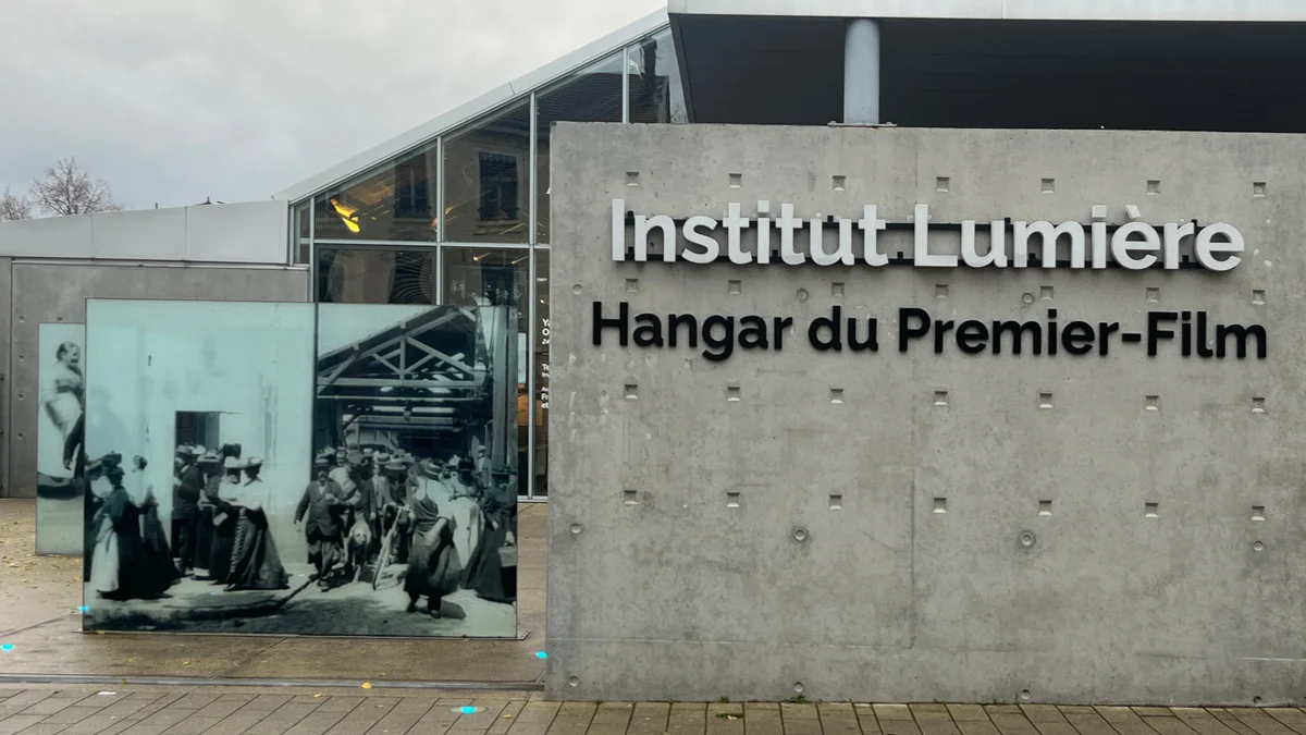 Parede com a inscrição Institut Lumière, Hangar du Premier-Film, ao lado de um painel fotográfico