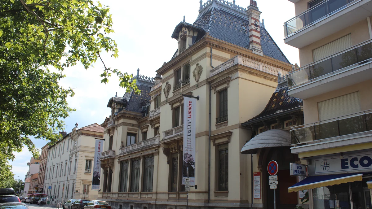 Fachada histórica do Institut Lumière vista de uma rua arborizada em Lyon