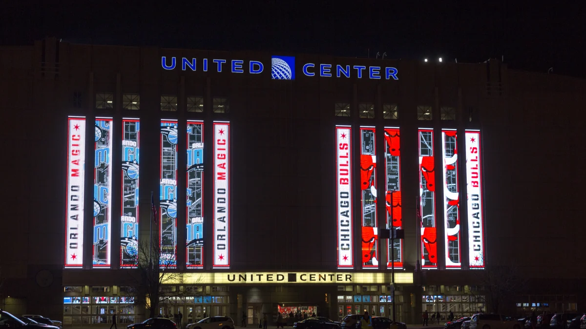 Fachada iluminada del United Center de noche con paneles de Chicago Bulls