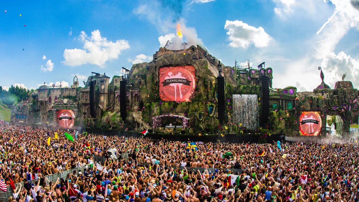 Crowd facing a large Tomorrowland stage under a blue sky