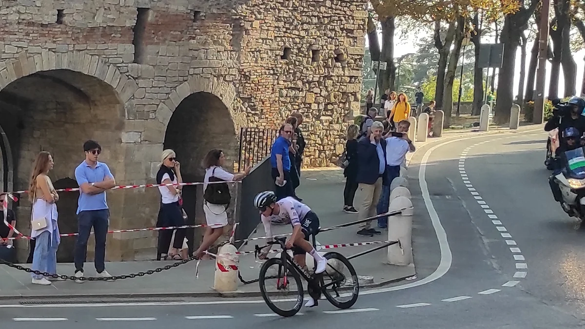 Un cycliste penché sur son vélo dans un virage près de remparts et de spectateurs
