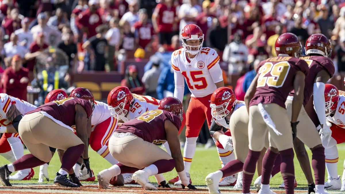 Patrick Mahomes derrière le centre pendant que les Chiefs et leurs adversaires s’alignent avant le snap