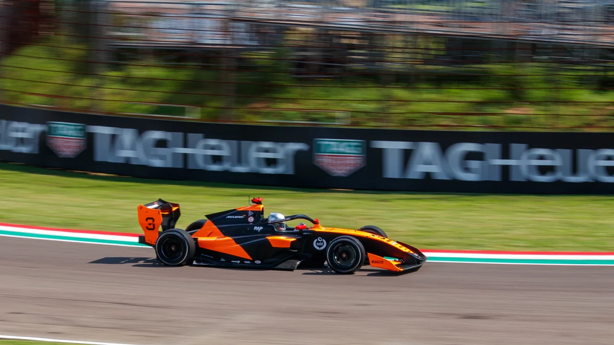 Carro laranja e preto de Fórmula 3 número 3 em movimento na pista