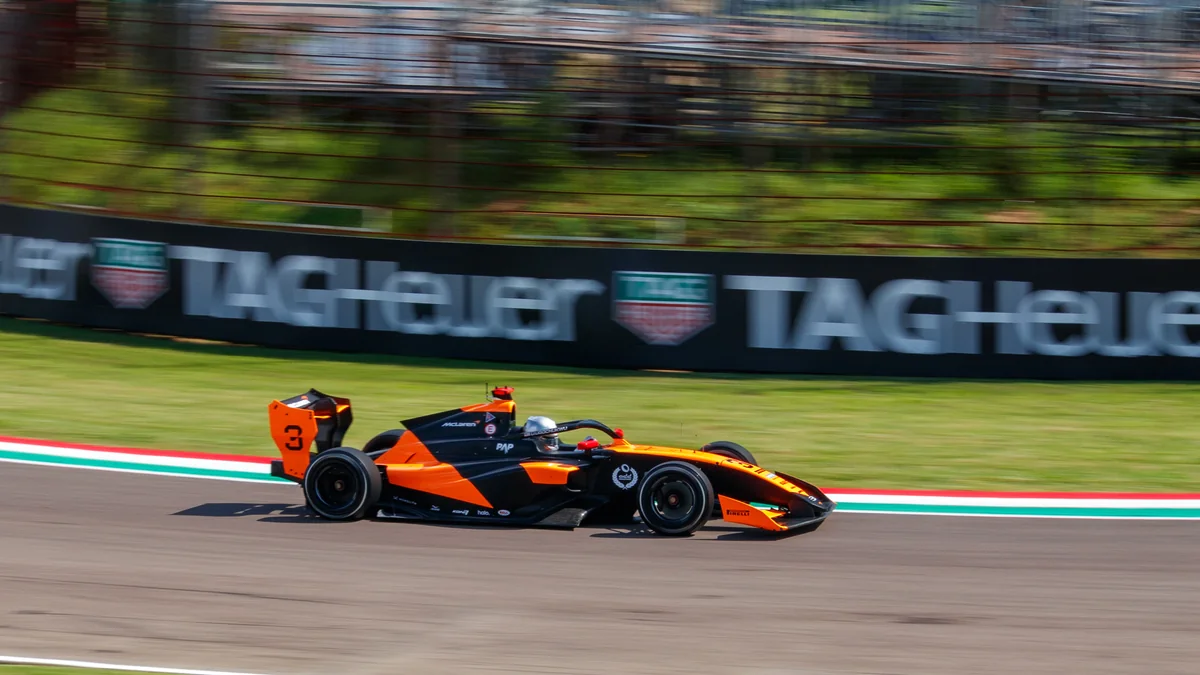Carro laranja e preto de Fórmula 3 número 3 em movimento na pista