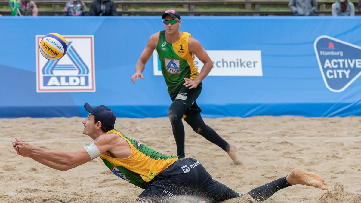 André Loyola Stein lunges for a low ball on the sand while George Wanderley follows the play