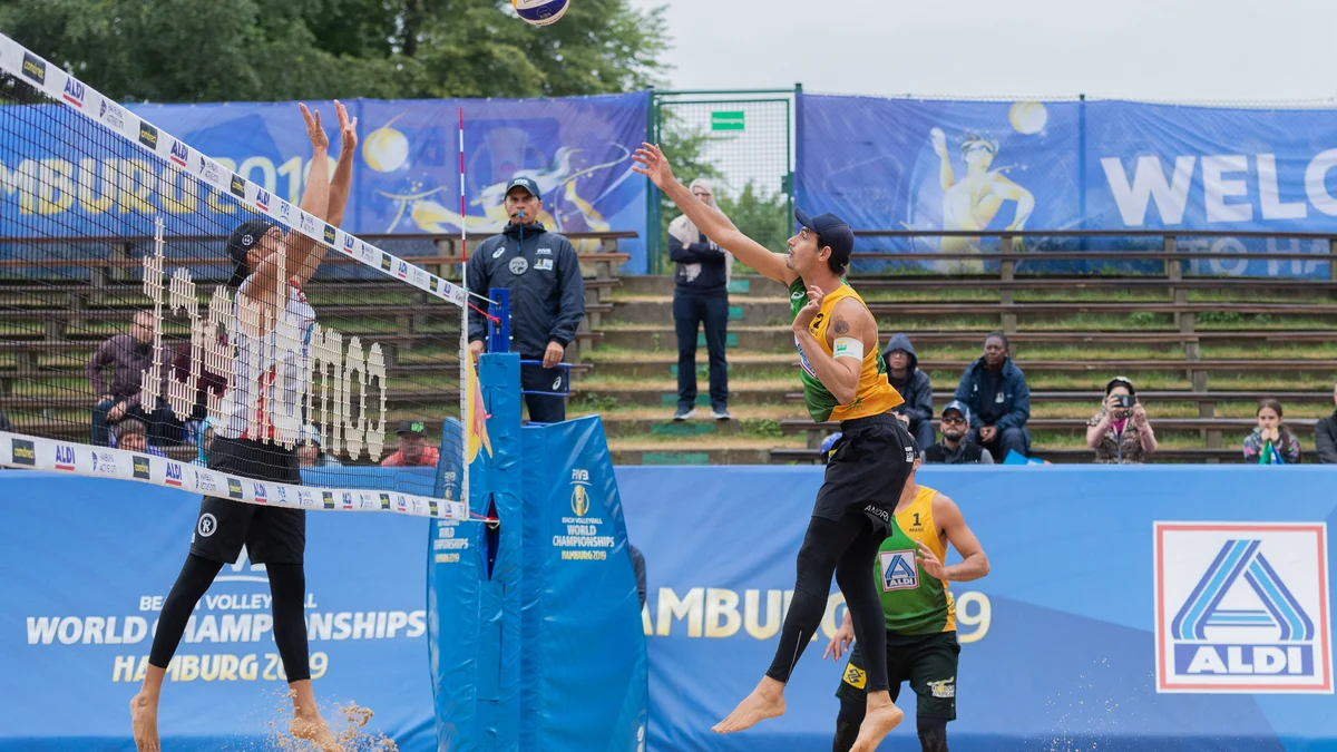 André Loyola Stein jumps beside the net to attack the ball against a blocker