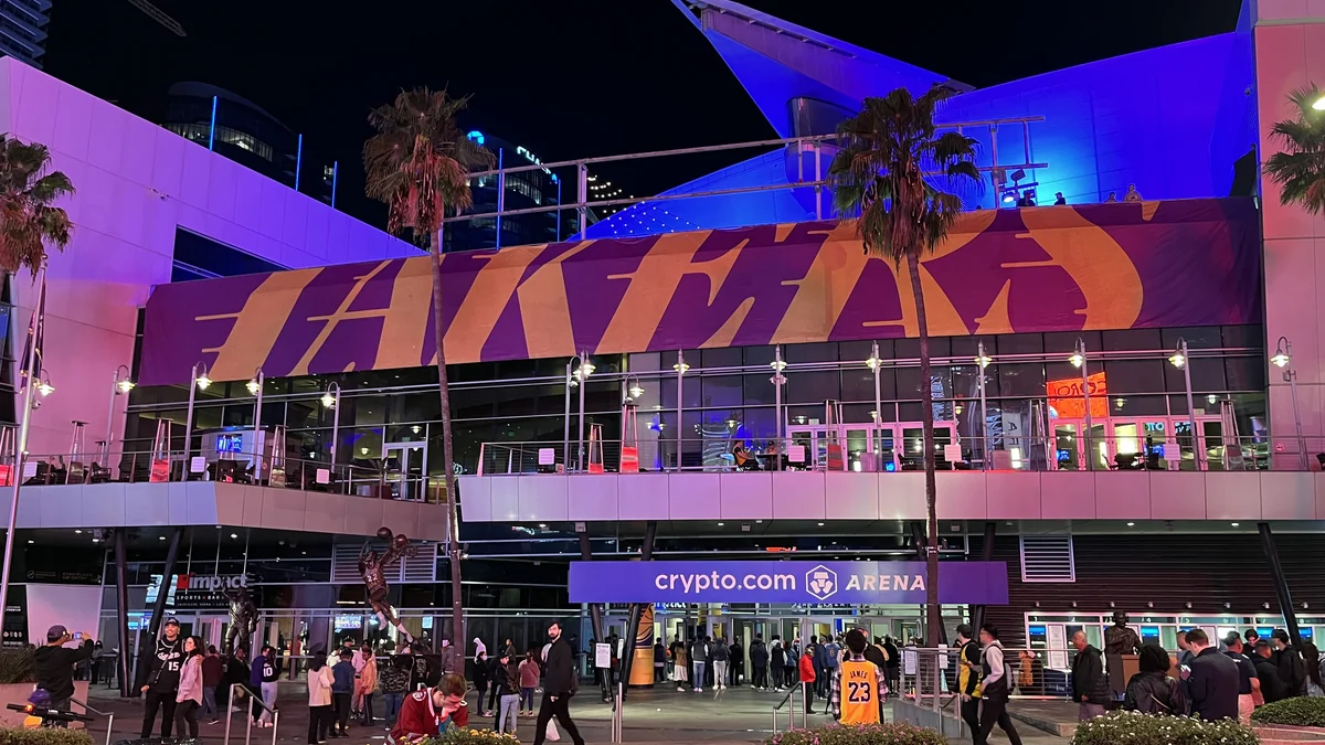 Star Plaza entrance of Crypto.com Arena at night, with palm trees, purple lighting and visitors by the doors