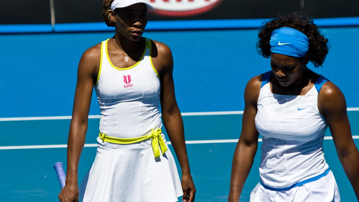Venus Williams et Serena Williams côte à côte sur un court de tennis bleu