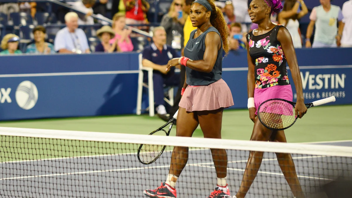 Serena Williams et Venus Williams, raquettes en main, près du filet pendant un match de double