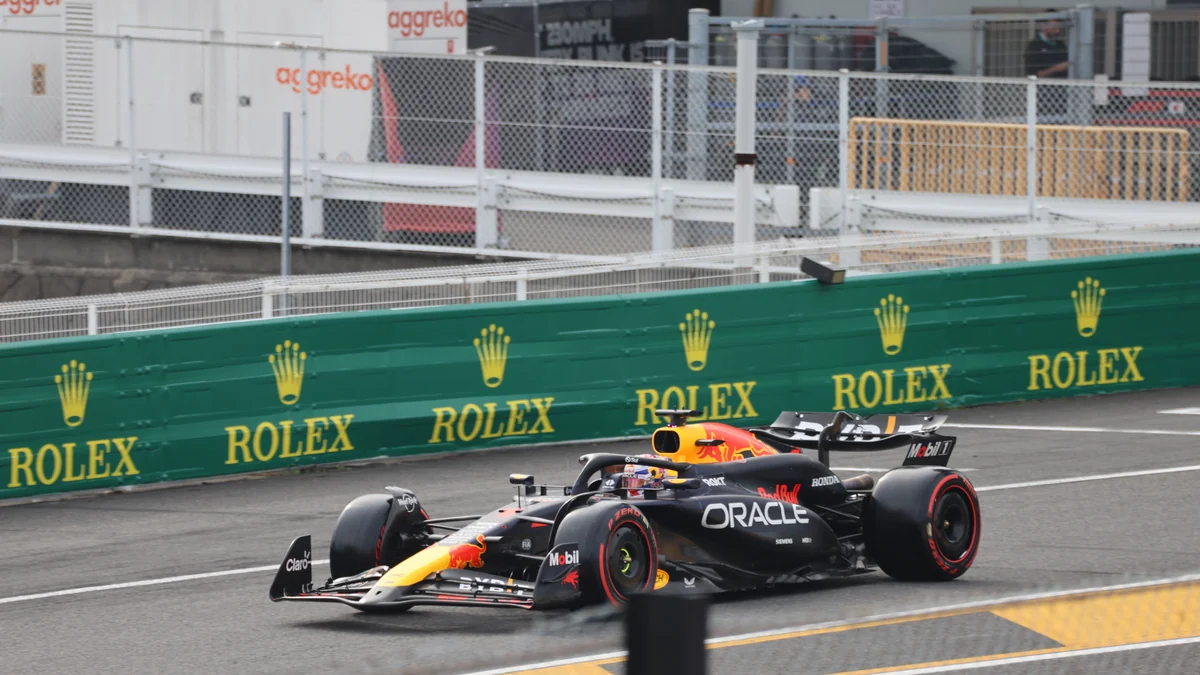 Monoplaza negro, rojo y amarillo de Red Bull toma una curva junto a barreras verdes