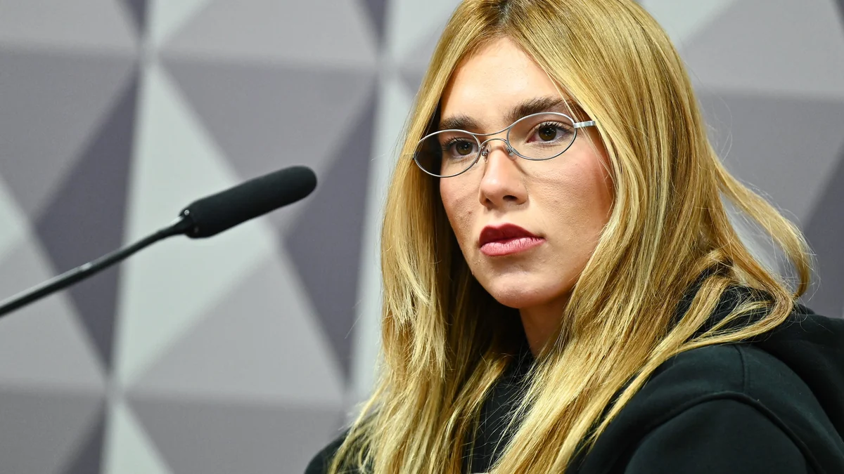 Virginia Fonseca, aux cheveux blonds et portant des lunettes, est assise devant un microphone.