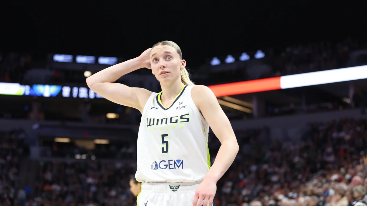 Paige Bueckers, en tenue blanche des Dallas Wings, porte une main à sa tête sur le terrain
