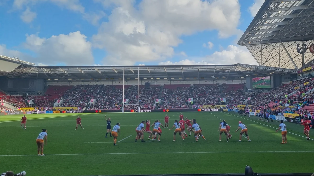 Des joueuses de rugby disputent une phase statique sur le terrain devant des tribunes remplies