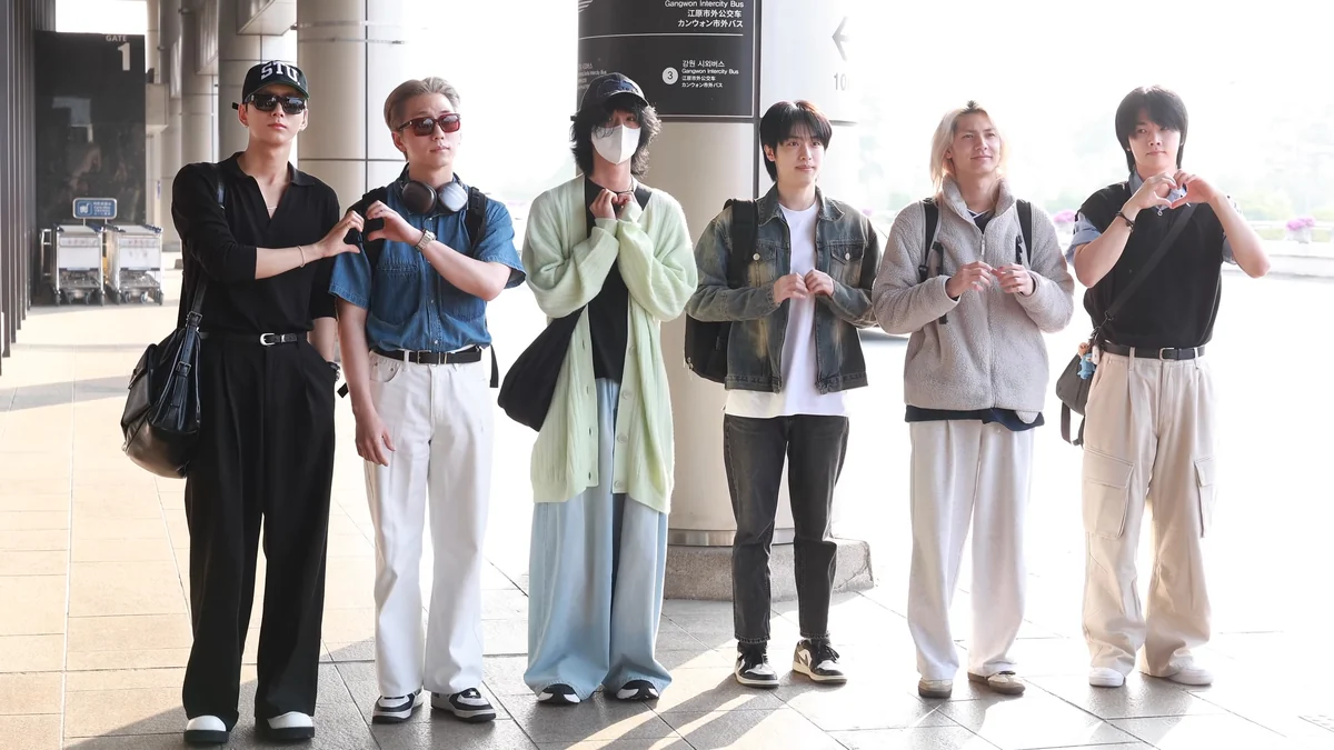 Seis integrantes de Xdinary Heroes posan juntos en una terminal de aeropuerto.
